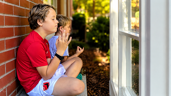 Two young boys meditating on stone bench