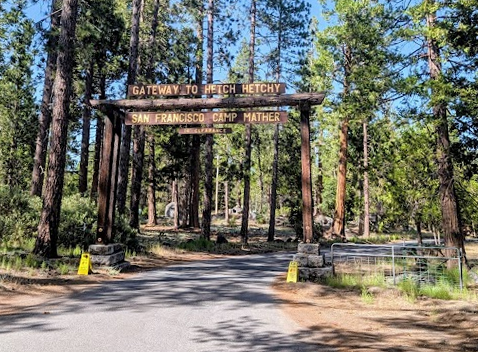 Wooden archway entrance to campground, surrounded by trees, that reads "Gateway to Hetch Hetchy: San Francisco Camp Mather"