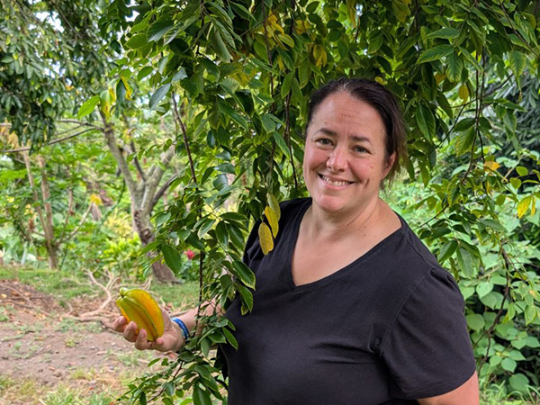 Smiling woman holding a star fruit in an orchard