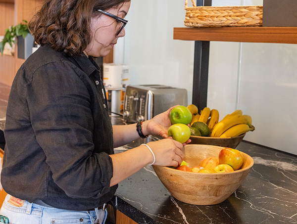 Woman filling a bowl of fruit for an office fruit program