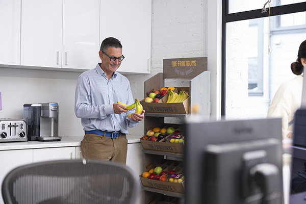 Man grabbing fresh fruit from a display in an office break room