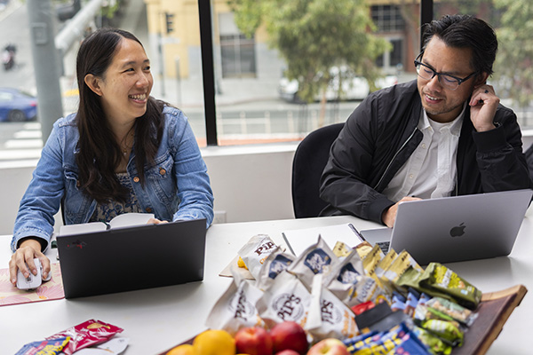 coworkers in a conference room working on laptops and smiling