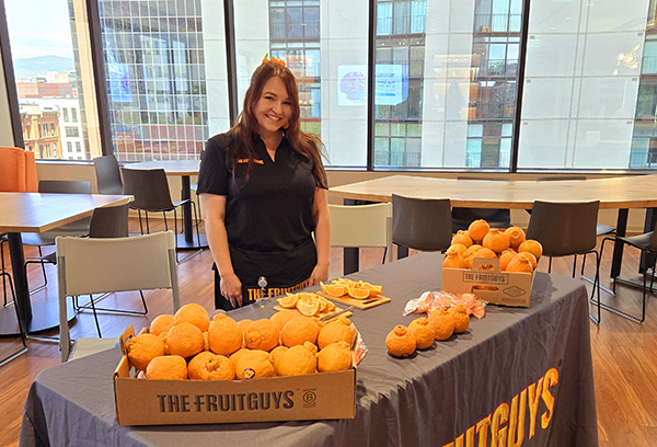 Smiling woman standing behind a table of fruit
