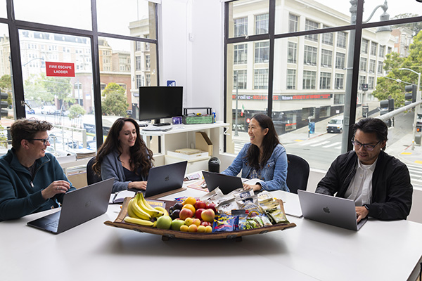 Employees working in the office with fruit and snacks in front of them
