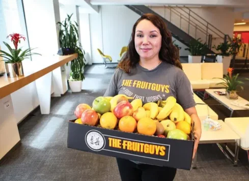 Woman carrying Fruitguys box with overflowing fruit